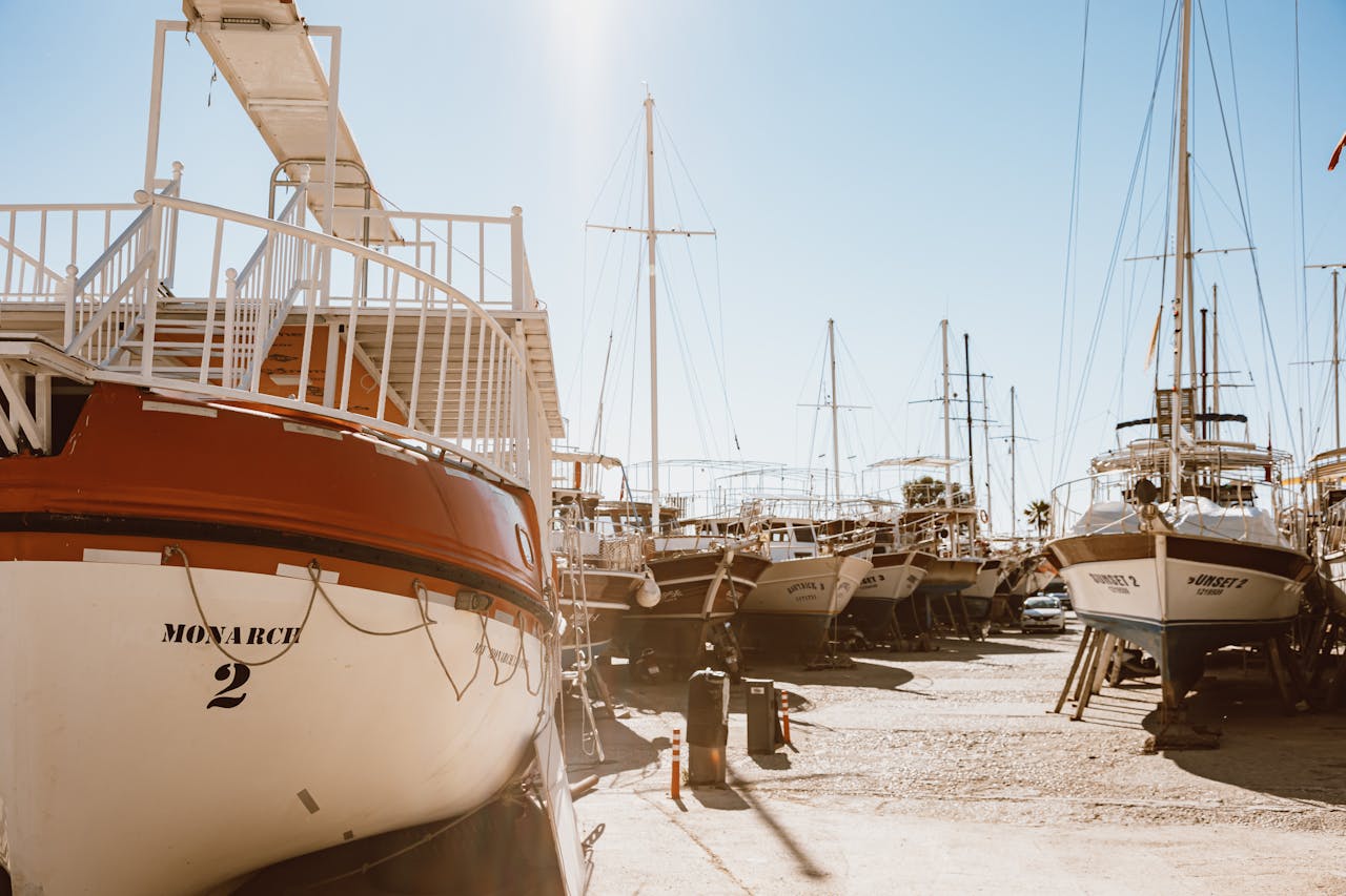 heros-img A peaceful view of a boat harbor with sailboats under a clear blue sky and ample sunlight.